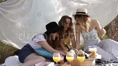 三个年轻漂亮女孩玩<strong>纸牌游戏</strong>的前镜头。 野餐，单身汉概念。 户外，白色的布